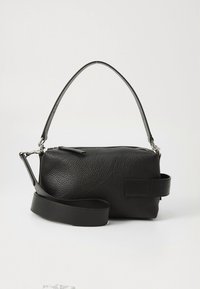 Black textured leather bag with a zip closure, featuring a short handle and adjustable strap. Smooth accents add contrast to the design.