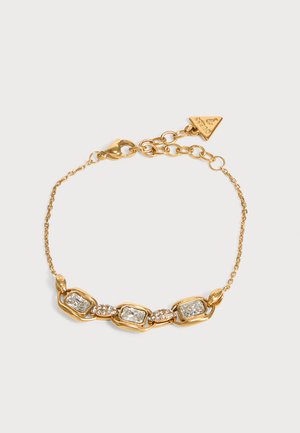 Bracelet chaîne en or avec trois pierres claires rectangulaires et de petits cristaux ronds entre elles, avec un fermoir en or et un pendentif triangulaire.