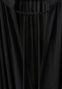 Zwarte kleding met een zachte, vloeiende stof, een diepe V-halslijn en een striksluiting. Het materiaal lijkt lichtgewicht en gestructureerd te zijn.