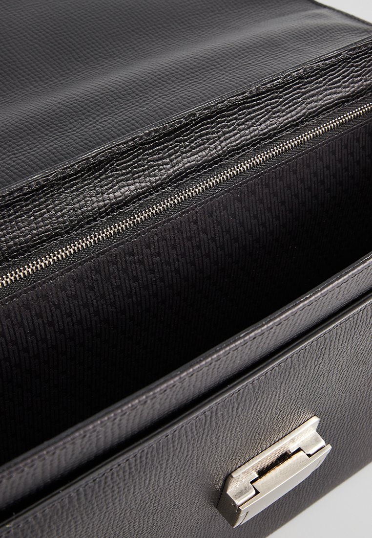 Zwarte textured leren aktetas geopend om de interieurstof voering en de zilveren metalen sluiting op de voorklep te tonen.