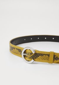 Ceinture en cuir jaune avec un motif en peau de serpent marron, dotée d'une boucle ronde en argent et de plusieurs trous d'ajustement.