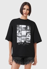 Camiseta negra de gran tamaño hecha de algodón. Presenta un gráfico de nueve fotos en blanco y negro con el texto "Verano Infinito" en blanco.