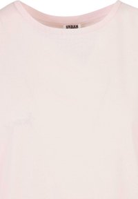 Jasnoróżowa koszulka z okrągłym dekoltem z widoczną metką marki Urban wewnątrz kołnierza.