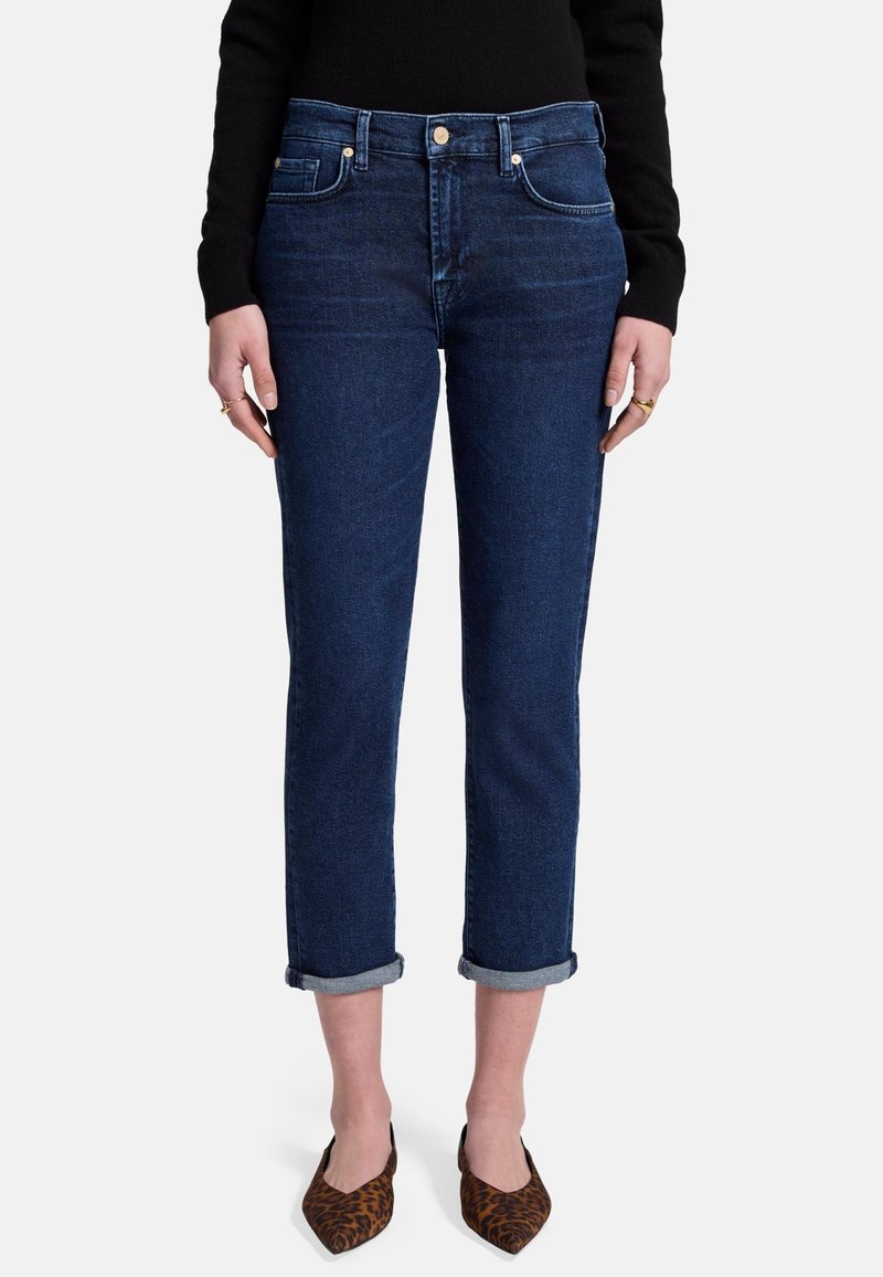 Donkerblauwe denim jeans met een rechte snit, opgerolde manchetten, vijf zakken en zilverkleurige hardware-details, gecombineerd met gedessineerde puntige flats.