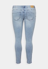 Jeans ajustados de color azul claro en tejido vaquero, con un diseño clásico de cinco bolsillos, cintura con una etiqueta de cuero y textura suave.