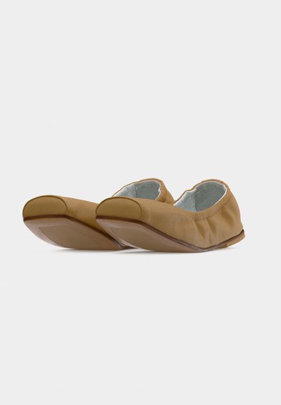 Ζεύγος απαλών μπεζ δερμάτινων μπαλαρινών με ελαστικές άκρες και μπεζ λαστιχένιες σόλες σε λευκό φόντο.