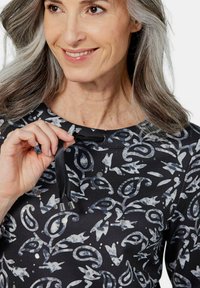 Zwarte top met grijs abstract bladerenpatroon, ronde halslijn en trekkoorddetails bij de kraag. Glad textuur en lichtgewicht stof.