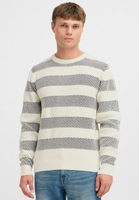 Light cream knitted sweater with navy horizontal stripes, ribbed neckline and cuffs, textured fabric, and a fitted design.