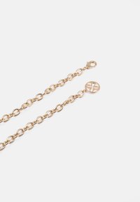 Zlato-tonirana kovinska veriga z medsebojnimi povezavami, opremljena z zaponko na oglobko in okroglo obeskom z detajliranjem cvetličnega vzorca.