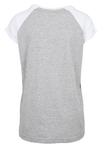 Camiseta gris de manga corta con un estilo raglán blanco. Tejido suave, cuello redondo, textura sutil y un corte relajado. Se muestra la vista posterior.