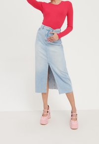 Jasnoniebieska midi spódnica z denimu z przednim rozcięciem. Połączona z jasnoczerwon�ą, prążkowaną bluzką z długim rękawem oraz różowymi butami na grubym obcasie.