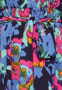 Färgglad textil med en blå bakgrund som har djärva abstrakta mönster i rosa, grönt och orange, accentuerad av en knytbeltdetalj.