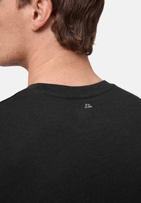 Svart bomull t-shirt med rund halsringning, med en subtil logotypdetalj nära ryggen, slät textur och standard passform.