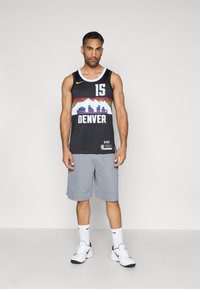 Mustat pelipaidat, joissa on valkoinen ja värikäs Denver-grafiikka, numero 15 ja keltainen Nike-logo. Yhdistetty harmaiden shortsien ja valkoisten lenkkarien kanssa.