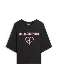 Černé tričko s krátkým rukávem vyrobené z bavlny. Na přední straně je výrazný nápis "BLACKPINK" v růžových písmenech a růžová grafika srdce.