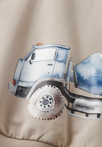 Illustration av en blå betongbil på beige tyg, som visar hytten, stora hjul och blandartrommel.