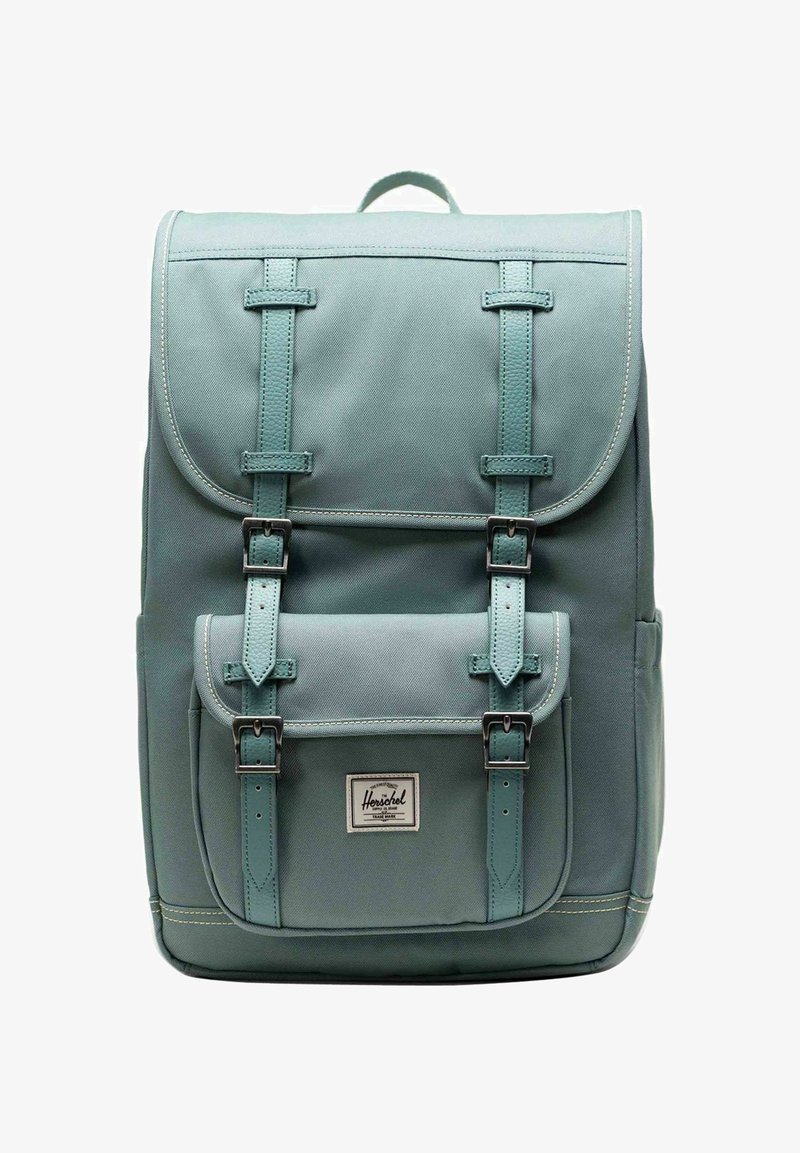 Sac à dos rectangulaire de couleur bleu sarcelle avec rabat et poche avant, sécurisé par deux sangles en cuir avec boucles en métal. Petite poignée en haut.