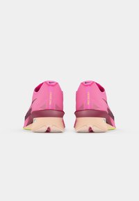Nike løpesko med en rosa mesh-overdel, svarte detaljer og en fleksibel såle med en grønn og beige gummi såle for grep.