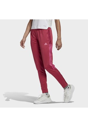 Pantalons de survêtement bordeaux avec trois bandes roses sur les côtés, taille élastique et jambes fuselées, assortis à des chaussures de sport blanches.