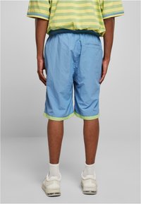 Gaiši zili šorti ar elastīgu jostu un zaļu apdari, ar gludu tekstūru un ceļgala garuma dizainu.