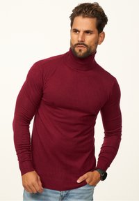 Burgunderfarbener Rollkragenpullover mit tailliertem Design, gerippten Bündchen und Saum. Hergestellt aus einem weichen, glatten Stoff ohne sichtbare Muster.