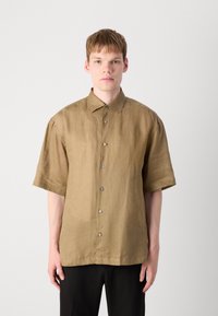 Korte mouwen shirt van een matte tan stof met een knoopsluiting aan de voorkant, relaxte pasvorm en zichtbare stikseldetails. Effen kleur zonder patronen.