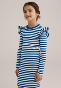 Gestreiftes Kleid mit blauen und weißen horizontalen Streifen, langen Ärmeln und gerafften Schulterakzenten. Glattes Strickmaterial; figurbetonte Form.