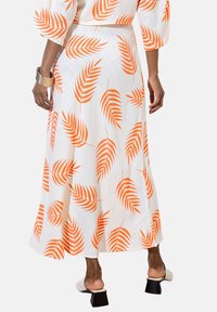 Jupe longue et fluide en tissu blanc avec un motif de feuilles orange vif. Texture lisse, forme légèrement évasée et longueur jusqu'aux chevilles.