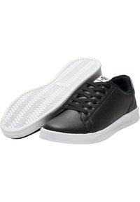 Baskets en cuir noir à finition lisse, semelle en caoutchouc blanche, bout rond et design classique à lacets. Présentent de petites perforations sur les côtés.