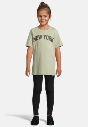 Šviesiai žalias medvilninis marškinėliai su „NEW YORK“ užrašu tamsiai pilka spalva, derinami su juodomis legginėmis ir juodais batais. Trumpomis rankovėmis, laisvas kirpimas.