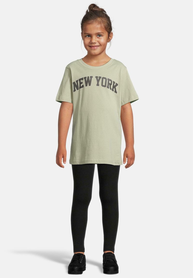 Šviesiai žalias medvilninis marškinėliai su „NEW YORK“ užrašu tamsiai pilka spalva, derinami su juodomis legginėmis ir juodais batais. Trumpomis rankovėmis, laisvas kirpimas.