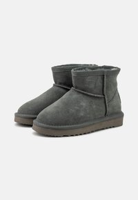 Stivaletti alla caviglia in suede grigio con una morbida fodera interna, dettagli cuciti, punta rotonda e suola in gomma texturizzata. Presentano un design con gambale più corto.
