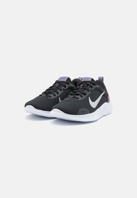 Crne atletske tenisice s prozračnom mrežastom gornjom dijelom, bijelim potplatom, ljubičastim akcentima na jeziku i peti, te reflektirajućim Nike swoosh logotipom.
