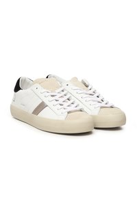 Een paar witte low-top sneakers met beige suède neusstukken, witte veters, zwarte hieltabs en lichtbruine strepen aan de zijkanten.