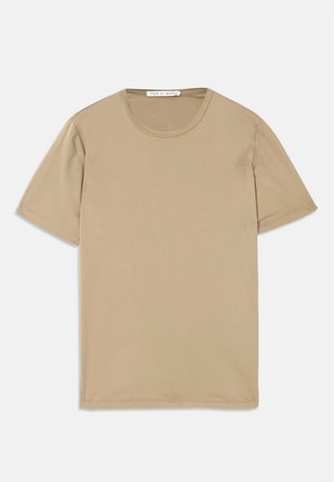 T-shirt beige a maniche corte realizzato in morbido cotone, con scollatura tonda e un design semplice e informale. Texture liscia, senza fantasie.