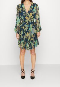 Květinové zavinovací šaty v navy barvě se zelenými, žlutými a tyrkysovými detaily. Průhledné dlouhé rukávy, výstřih do V a volánkový lem.