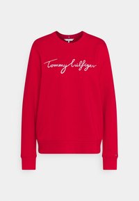 Rode sweatshirt met lange mouwen, ronde halslijn en witte "Tommy Hilfiger" logo in cursief over de borst. Katoenen materiaal met geribbelde cuffs.