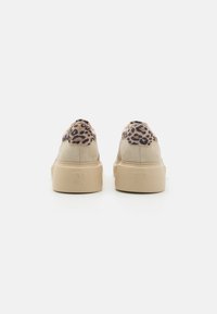 Baskets à imprimé léopard avec une partie supérieure en suède beige et une semelle en caoutchouc tan, présentant un design basse et un logo embossé au niveau du talon.