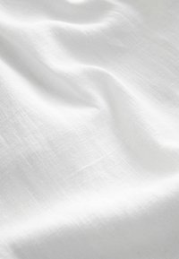 Valge kangas, millel on sile, kergelt kortsus tekstuur, mis omab kerget ja hingavat omadust, näidates ühtlast ja peent kudumist.