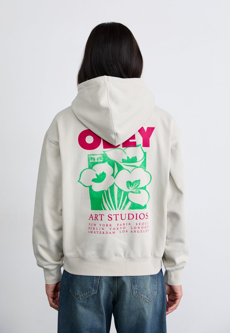 Hooded sweatshirt in light gray with a large green floral graphic and pink text on the back, featuring ribbed cuffs and hem.