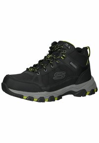 Botas de senderismo negras con un upper texturizado, acentos verdes y una suela de goma gris resistente. Cuenta con ojetes reforzados y un collar acolchado.