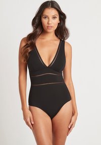 Zwarte badpak met een diepe halslijn, verstelbare bandjes en horizontale mesh-accenten rond de taille. Gladde stof, aansluitend ontwerp.