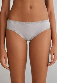 Lichtgrijze hipsteronderbroek met kanten rand, gemaakt van een zachte stof en voorzien van een subtiele elastische tailleband. Heeft gegolfde kanten randen op de taille.