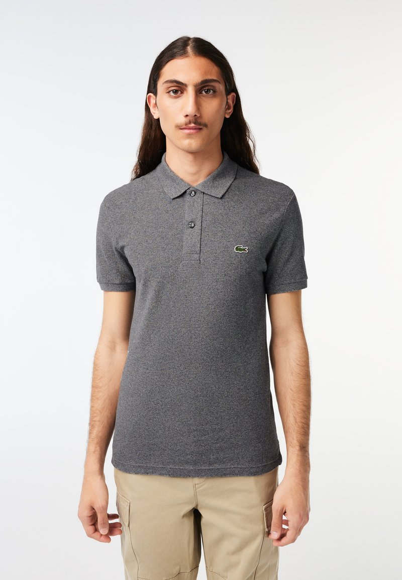 Camisa polo gris hecha de tela texturizada, con un cuello, tres botones y un pequeño logo verde en el lado izquierdo del pecho. Mangas cortas.