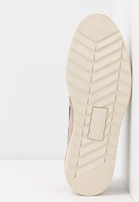 Semelle de basket en caoutchouc crème avec un motif de bande de roulement en zigzag. Tige en suède rose clair avec un détail décoratif cousu le long du côté.
