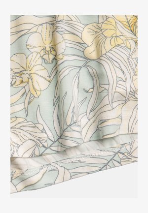 Bloemrijke stof met grote gele en crèmekleurige orchids op een licht muntgroene achtergrond, met zichtbare stiksels langs de randen.