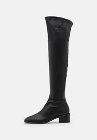 Bota negra por encima de la rodilla, hecha de material suave, con punta afilada y tacón de bloque, con un detalle de logo embossado en la parte superior.
