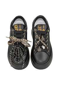 Le sneakers in pelle nera presentano lacci neri, occhielli dorati e un nastro decorativo con stampa leopardata. Decorazioni con perline e ciondoli aggiungono dettagli.