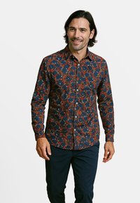 Donkerblauwe blouse met een bloemenpatroon in rood en wit. Lange mouwen en een puntige kraag. Gemaakt van een zachte stof.