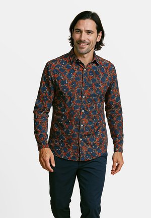 Donkerblauwe blouse met een bloemenpatroon in rood en wit. Lange mouwen en een puntige kraag. Gemaakt van een zachte stof.